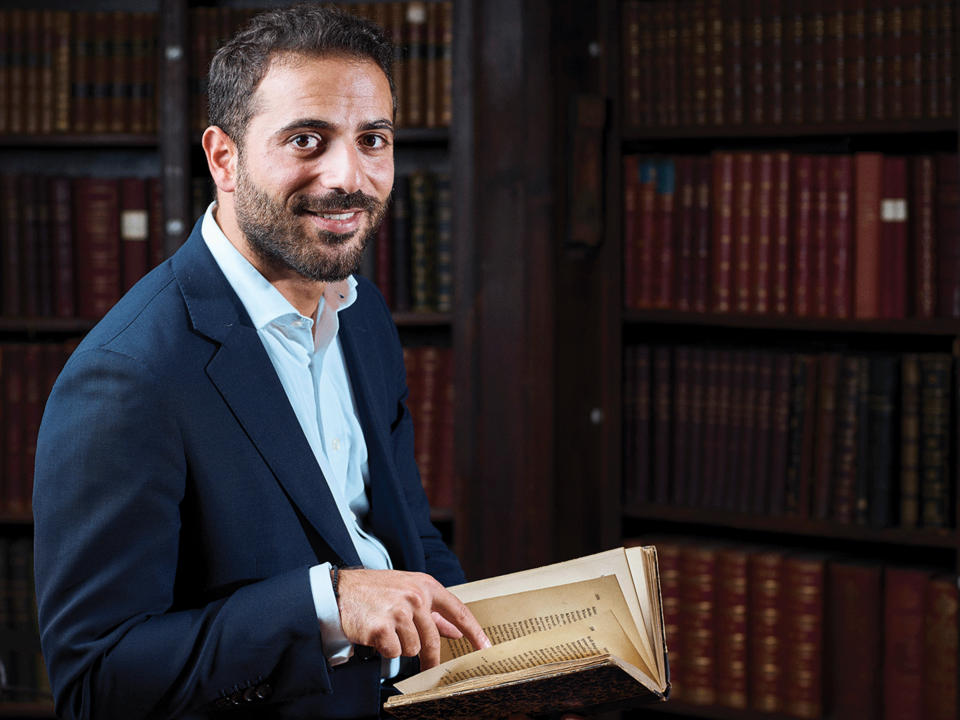 A young lawyer poses with an old book in his hand inside a library