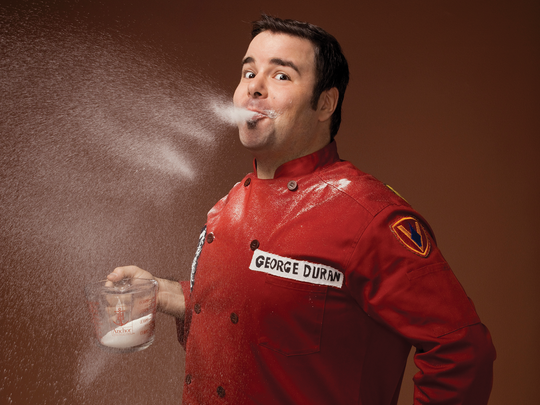 A chef wearing a red suite and having fun with sugar