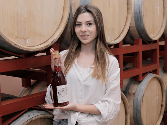 A young winemaker lady with her branded wine bottle