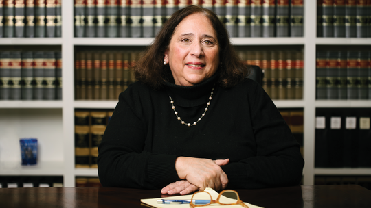 Female attorney in her office, sitting with law books behind her